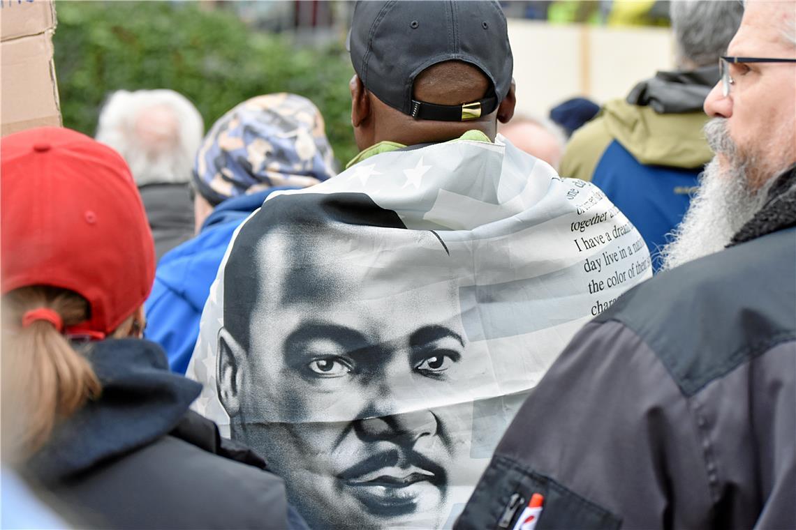 Ein Teilnehmer trägt eine Fahne mit dem Portrait von Martin Luther King als Umha...