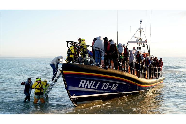 Eine Gruppe von Menschen wird von der Royal National Lifeboat Institution (RNLI) nach einem Zwischenfall mit einem kleinen Boot im Ärmelkanal nach Dungeness in der Grafschaft Kent gebracht