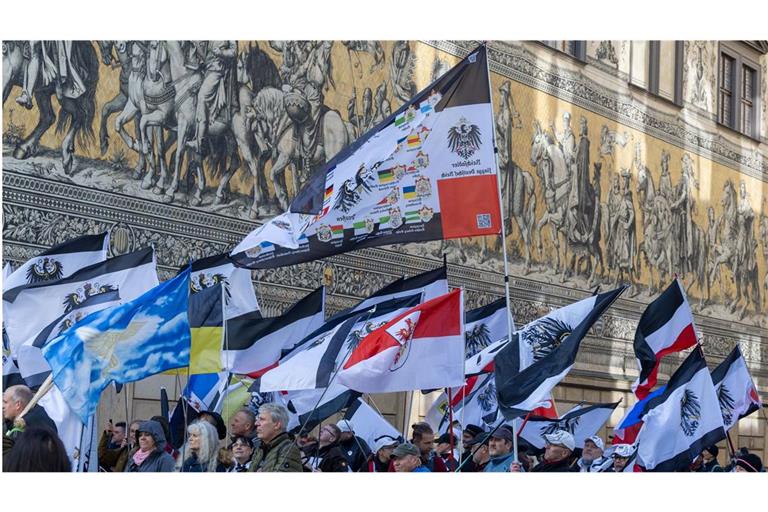 Mehrere hundert Teilnehmer einer Demonstration ziehen mit Flaggen vom Königreich Preußen(schwarz-weiß-schwarz mit Adler) über die Augustusstraße am Fürstenzug in Dresden vorbei (Foto vom 28. Oktober 2023)